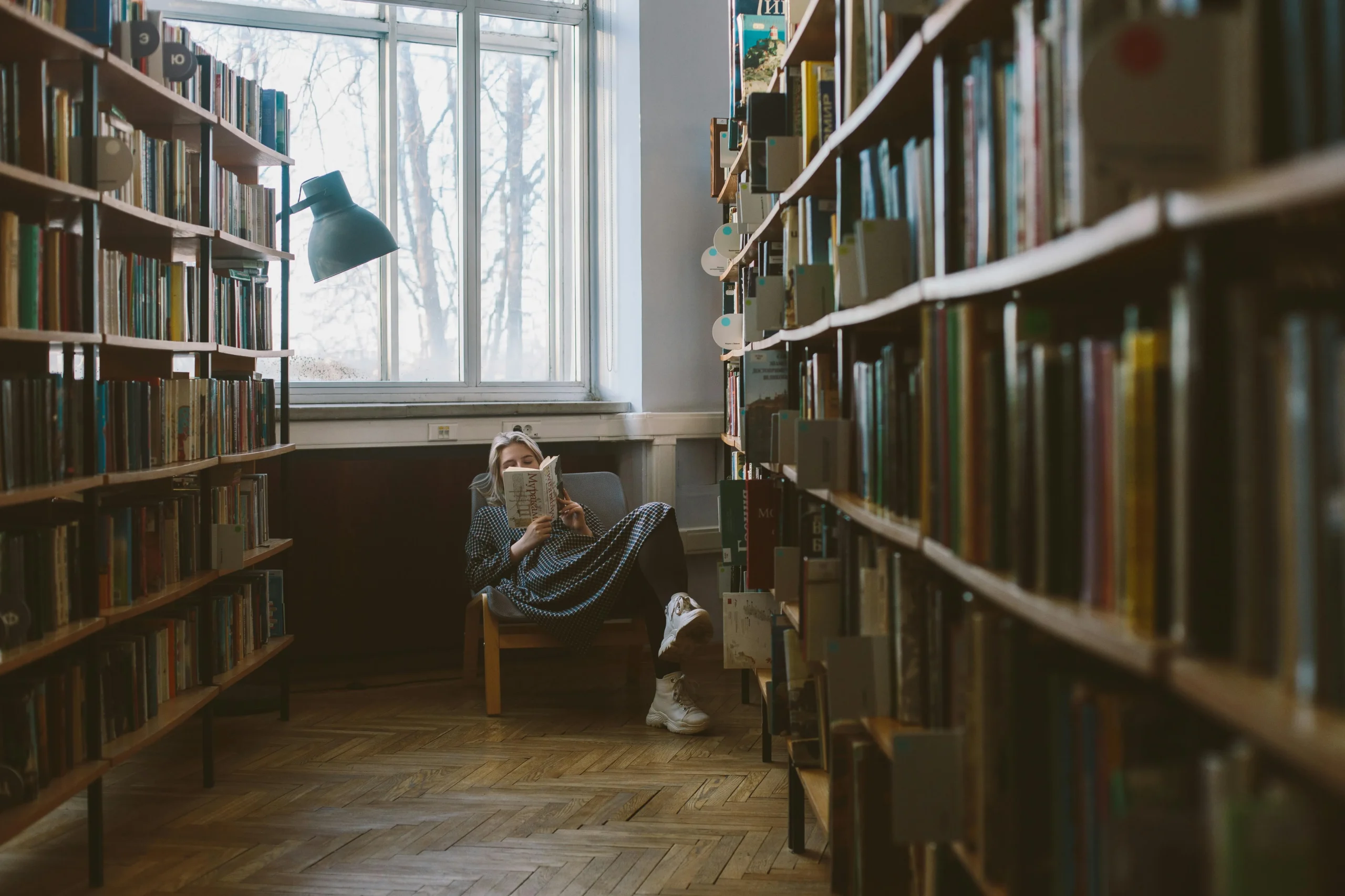 A_cozy_chair_with_a_blanket_and_lamp_next_to_an_open_book_in_night_lighting